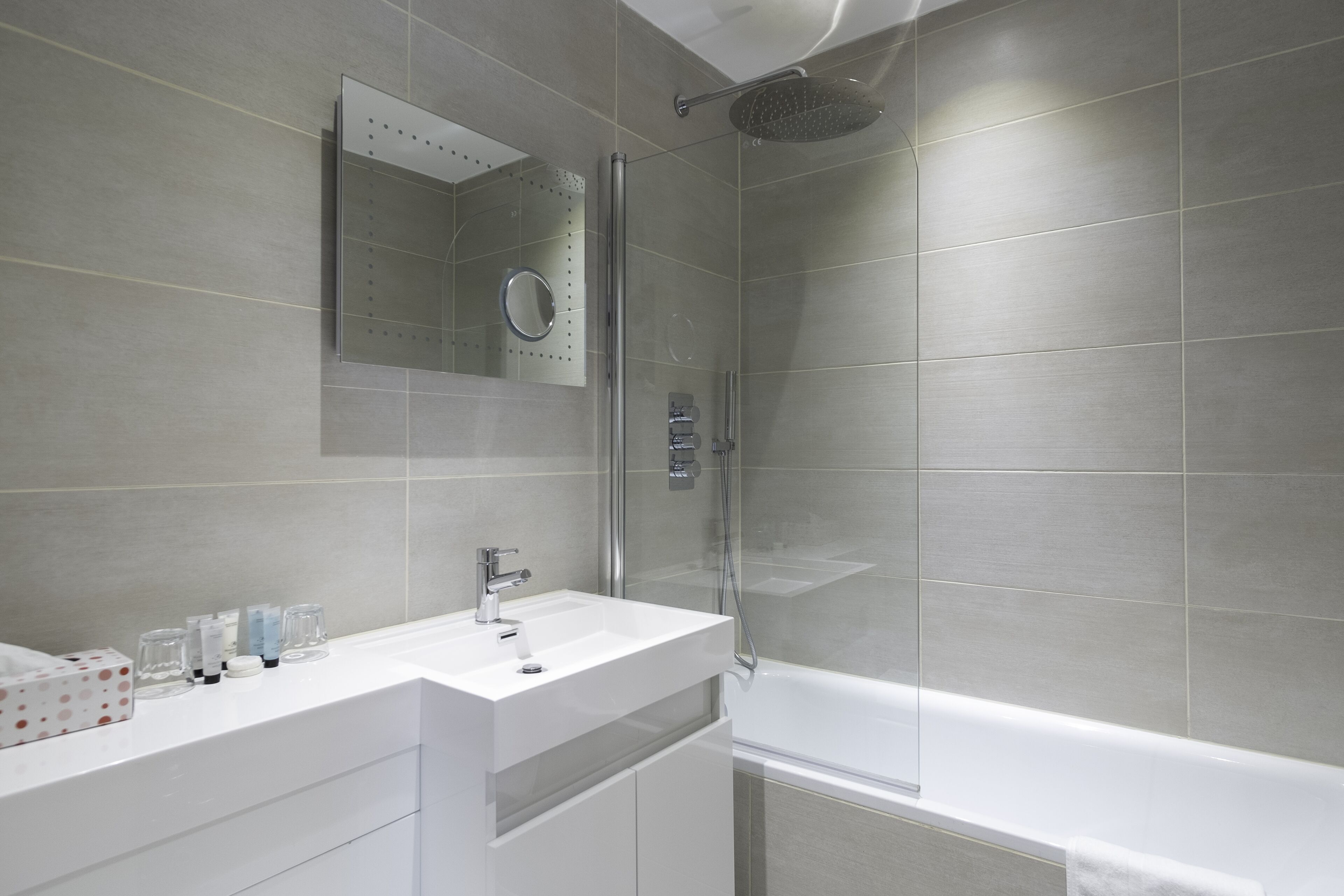 A modern bathroom with a white vanity, a glass shower enclosure, and a large bathtub.