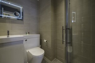 Een moderne badkamer met toilet, wastafel en douche.