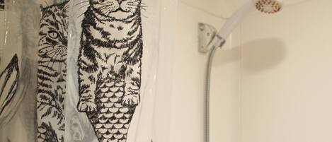 Un baño con cortina de ducha estampada con un diseño de gatos.