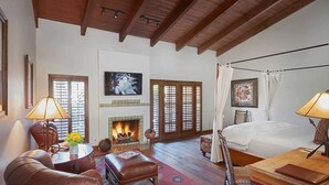 A spacious room with a fireplace, a bed with a canopy, leather furniture, and artwork on the walls. - Hermosa Inn (Paradise Valley)