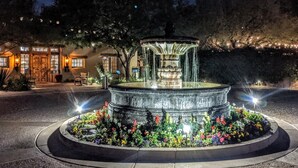 A well-lit fountain with a circular base, surrounded by a flower bed. - Hermosa Inn (Paradise Valley)