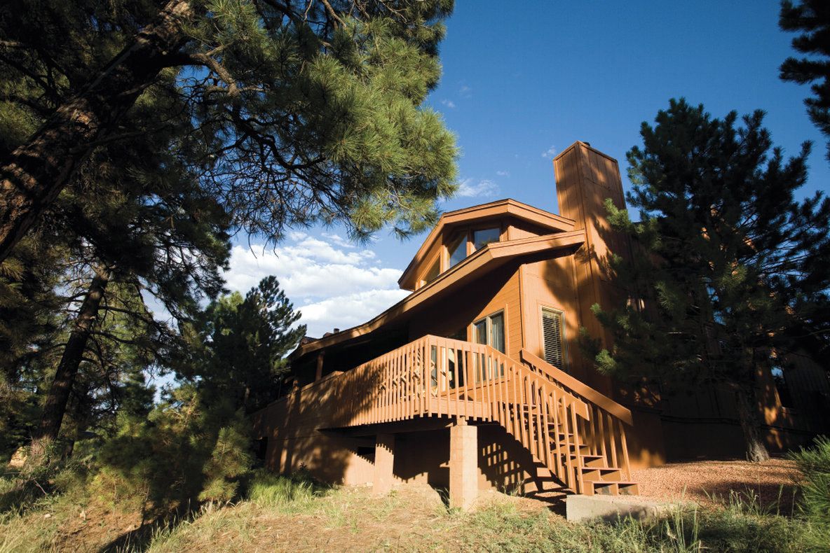 A cabin with a wooden exterior, a balcony, and a chimney.