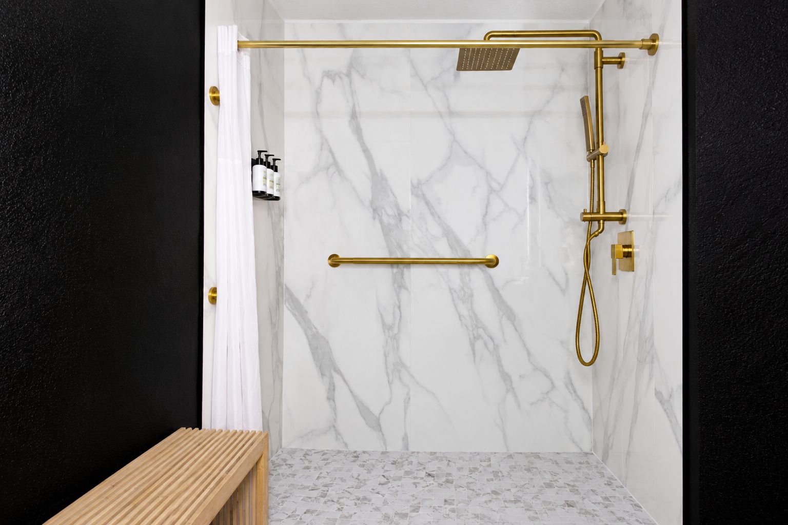 Une salle de bain moderne avec une douche, des murs en marbre et des accessoires dorés.
