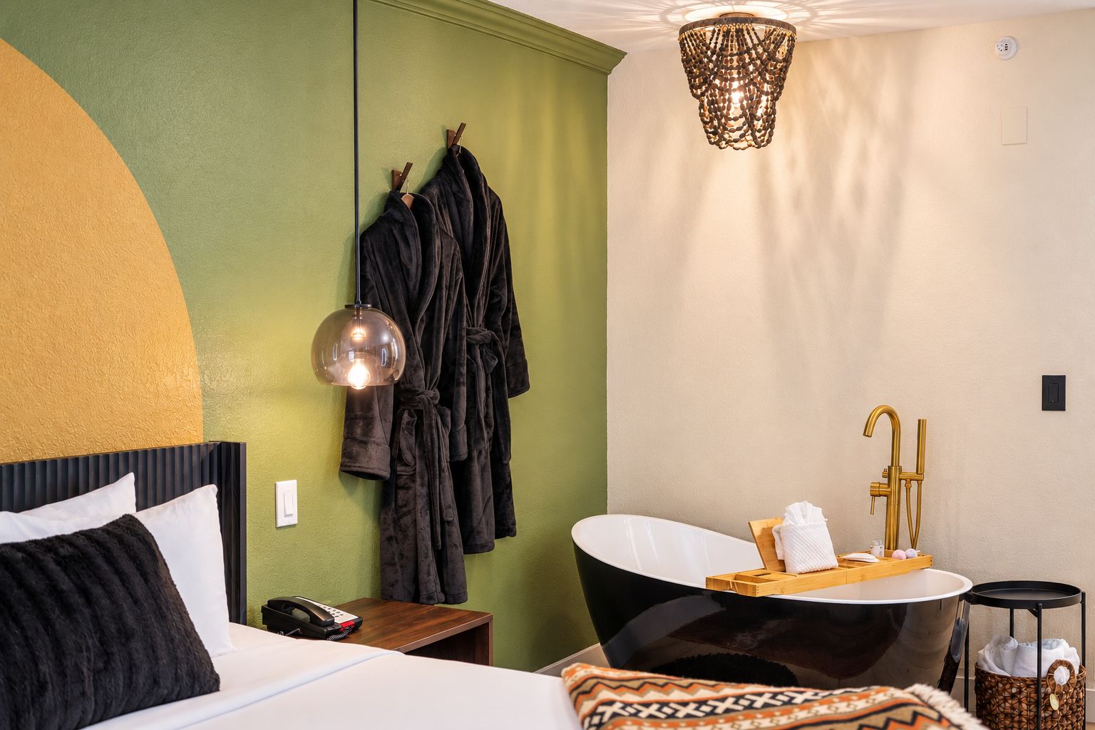 Habitación de hotel con cama, tocador con bañera y perchero para bata.