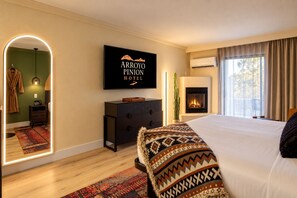 A hotel room with a bed, a television mounted on the wall, a fireplace, and a large mirror. - Arroyo Pinion Hotel, an Ascend Collection Hotel (Sedona)