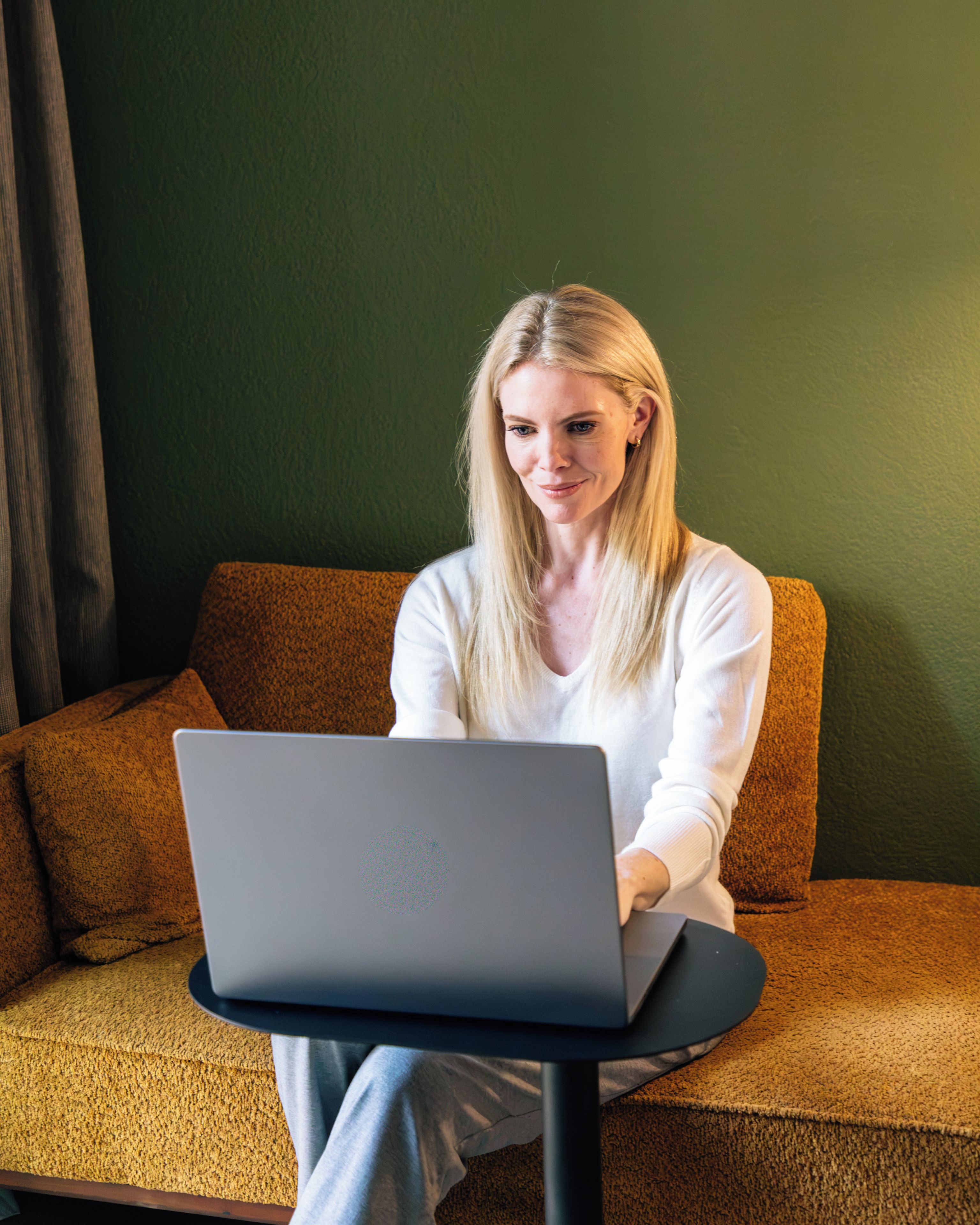 A person sitting on a brown sofa with a laptop on a small table.