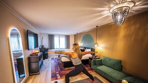 A room with a bed, a green sofa, a mirror, a desk, and a yoga mat. - Arroyo Pinion Hotel, an Ascend Collection Hotel (Sedona)