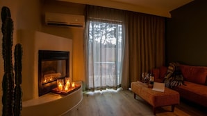 A cozy living room with a fireplace, a couch, a coffee table, and a cactus plant. - Arroyo Pinion Hotel, an Ascend Collection Hotel (Sedona)