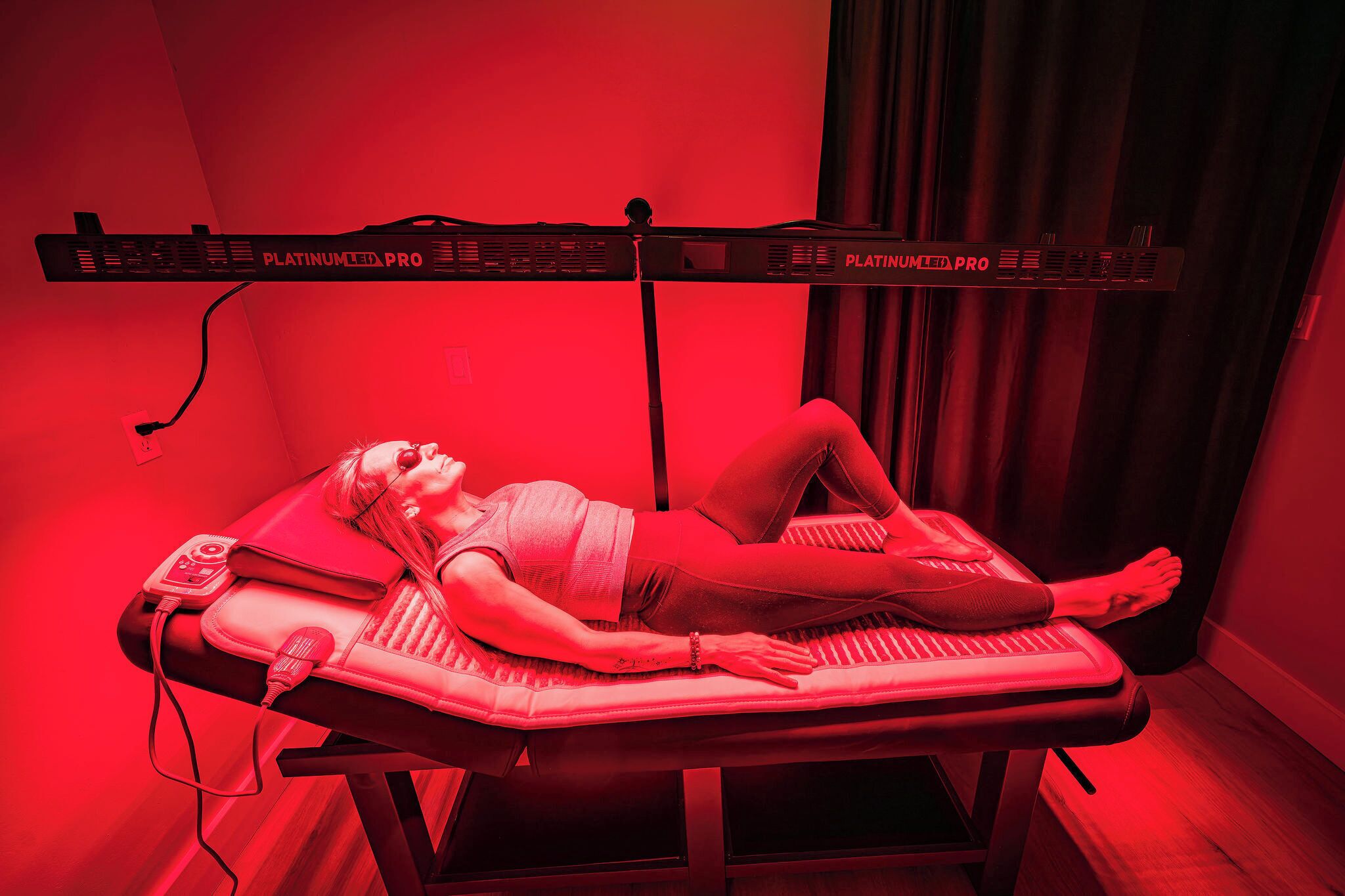 A person lying on a massage table with a foot massager and a foot reflexology table.