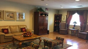A living room with a sofa, two plaid armchairs, a coffee table, a rug, a cabinet, and a bookshelf. - Baymont by Wyndham Mount Vernon Renfro Valley (Mount Vernon)