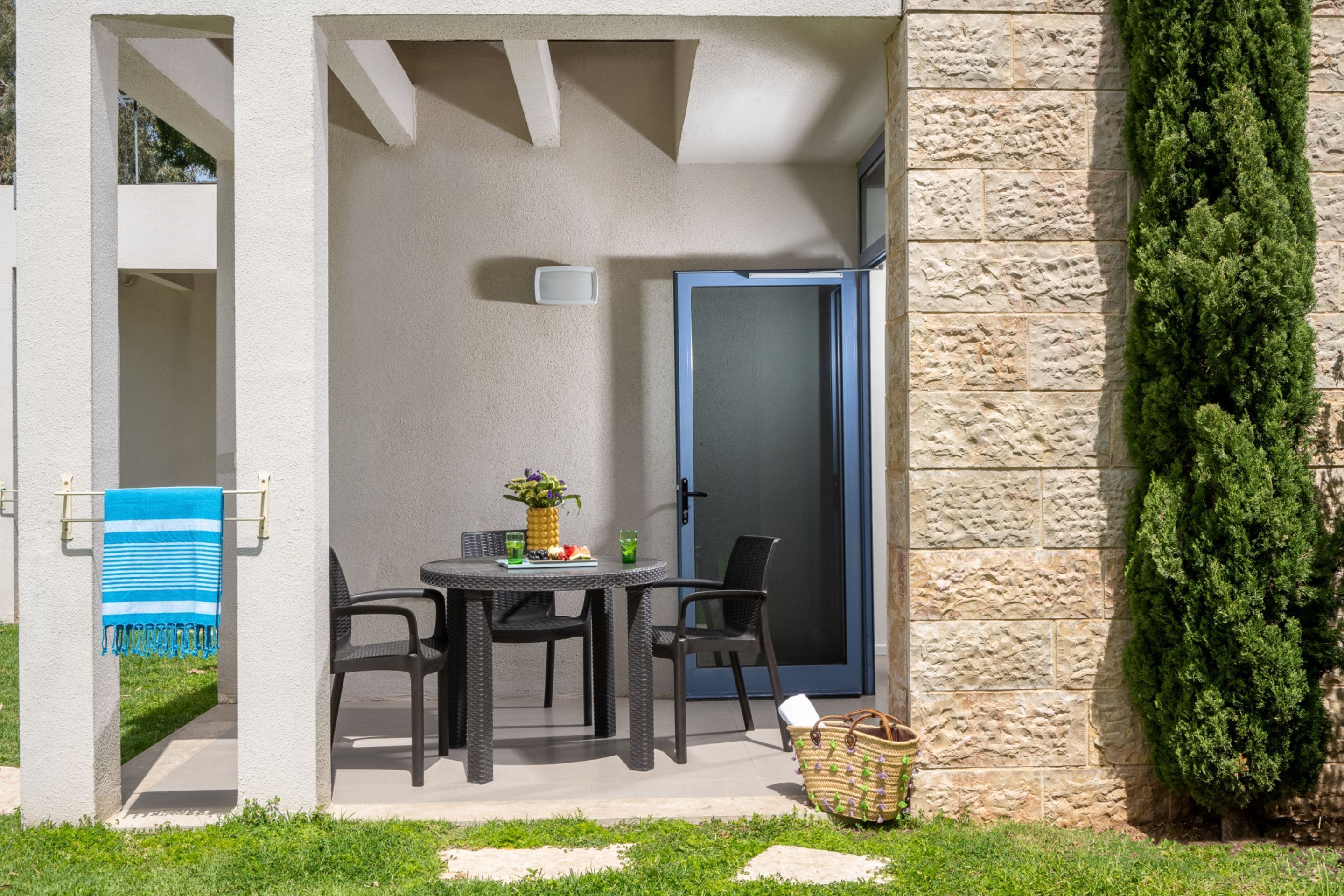 An outdoor patio with a table and chairs, a door, and a stone wall.