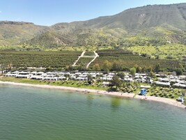Un complejo turístico frente al mar con villas, una playa y montañas al fondo.