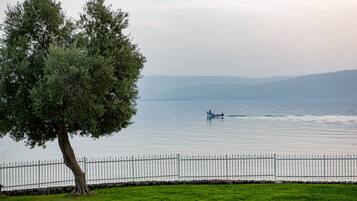 A lake with a boat, a tree, and a white fence.
