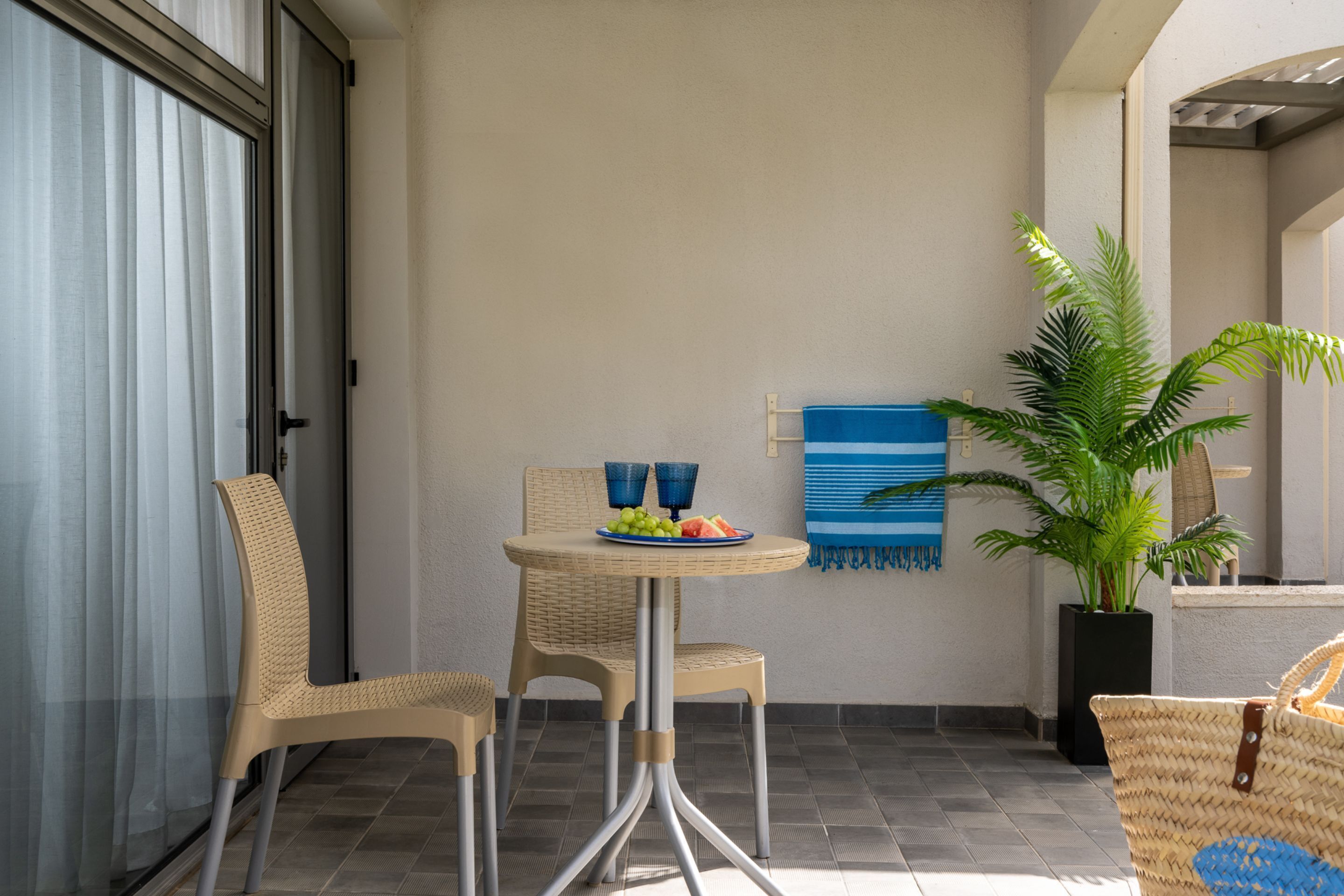 Een terras met rieten meubels, een tafel met een schaal fruit en een potplant.
