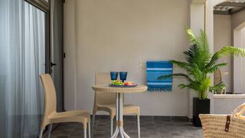 A patio with wicker furniture, a table with a plate of fruit, and a potted plant.