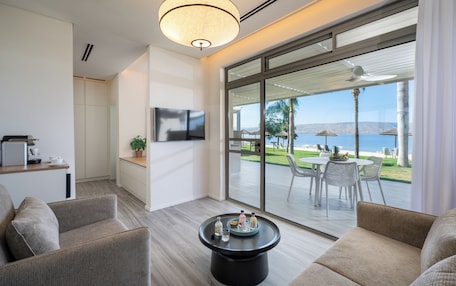 A modern living room with a large sliding glass door leading to an outdoor patio with a view of the beach.