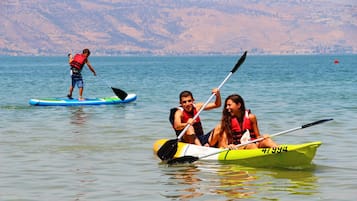 Un grupo de personas haciendo kayak en un lago tranquilo con colinas al fondo.