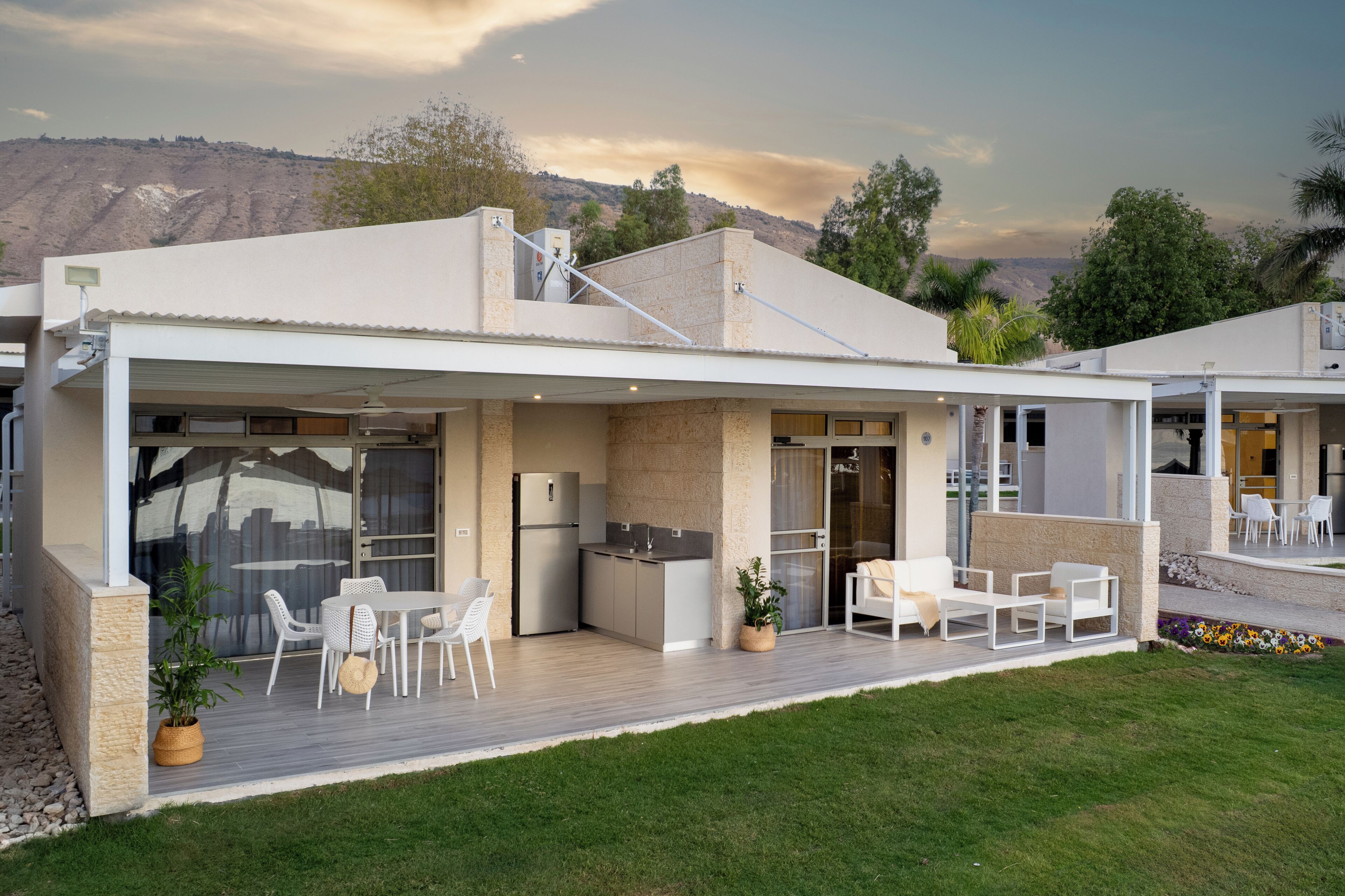 A modern house with a covered patio, outdoor seating, and a kitchen area.