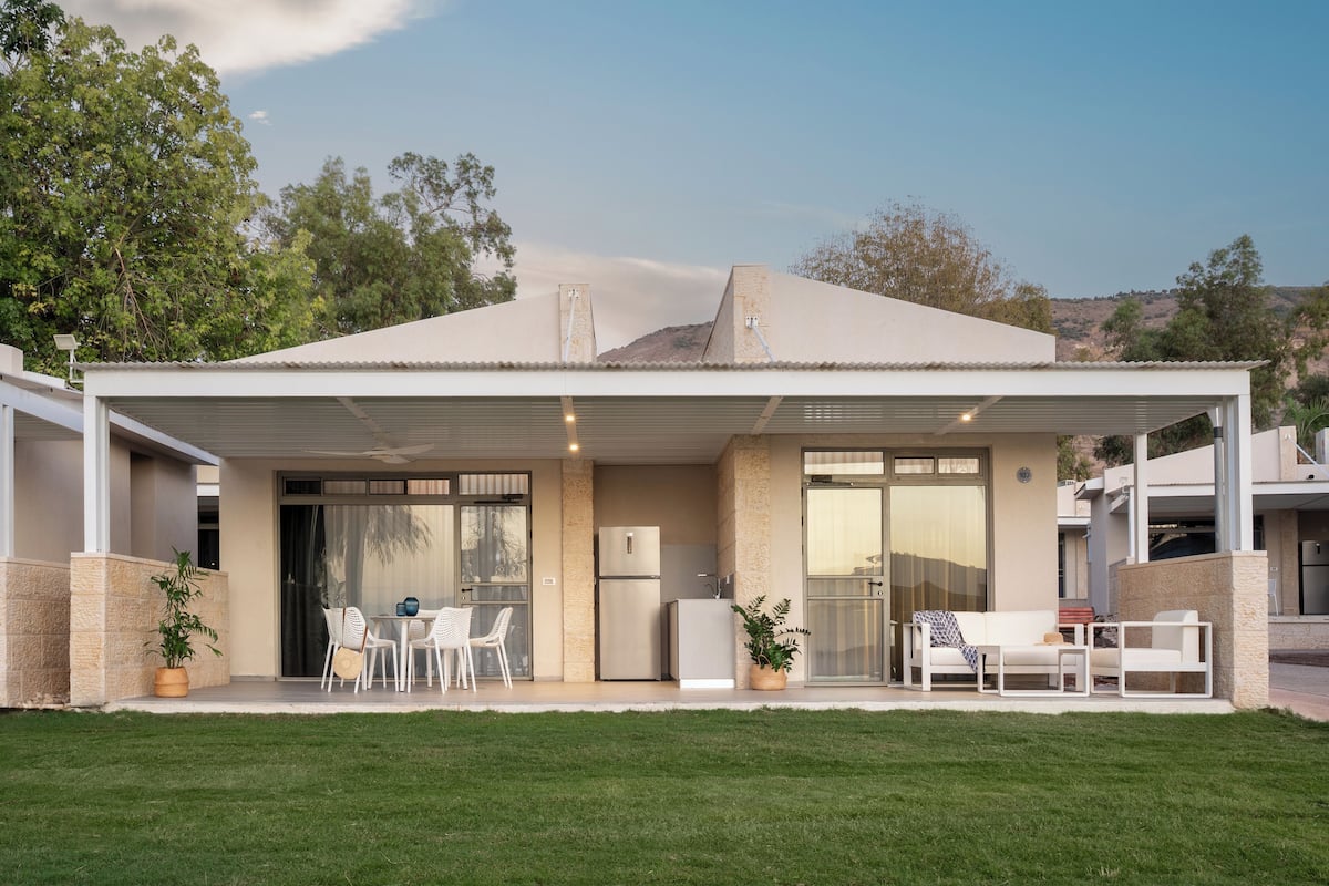 A modern house with a covered patio, a kitchen area, and a seating area with outdoor furniture.