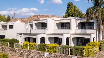 Una hilera de edificios blancos de varios pisos, con balcones, un muro de piedra y un letrero que indica las habitaciones 521-530.