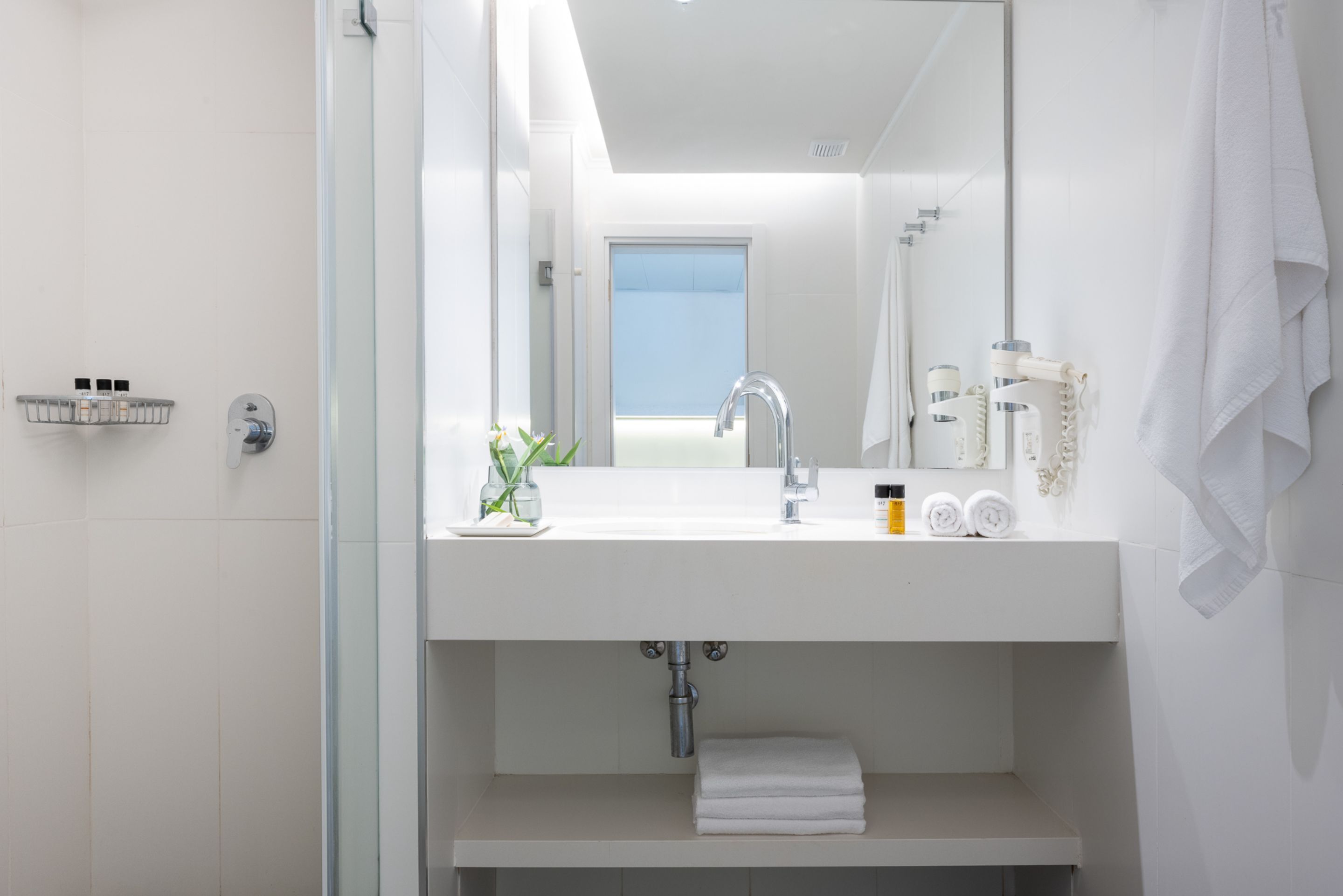 A modern bathroom with a white sink, mirror, and towel rack.