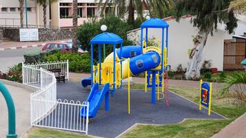Kids can play on the slide and climbing structures within the fenced area.