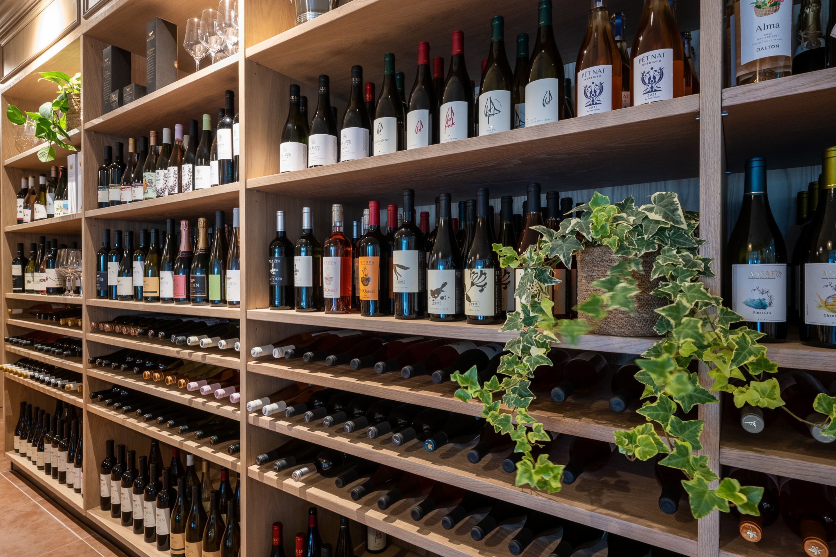 Una bodega con estantes llenos de botellas de vino y copas.