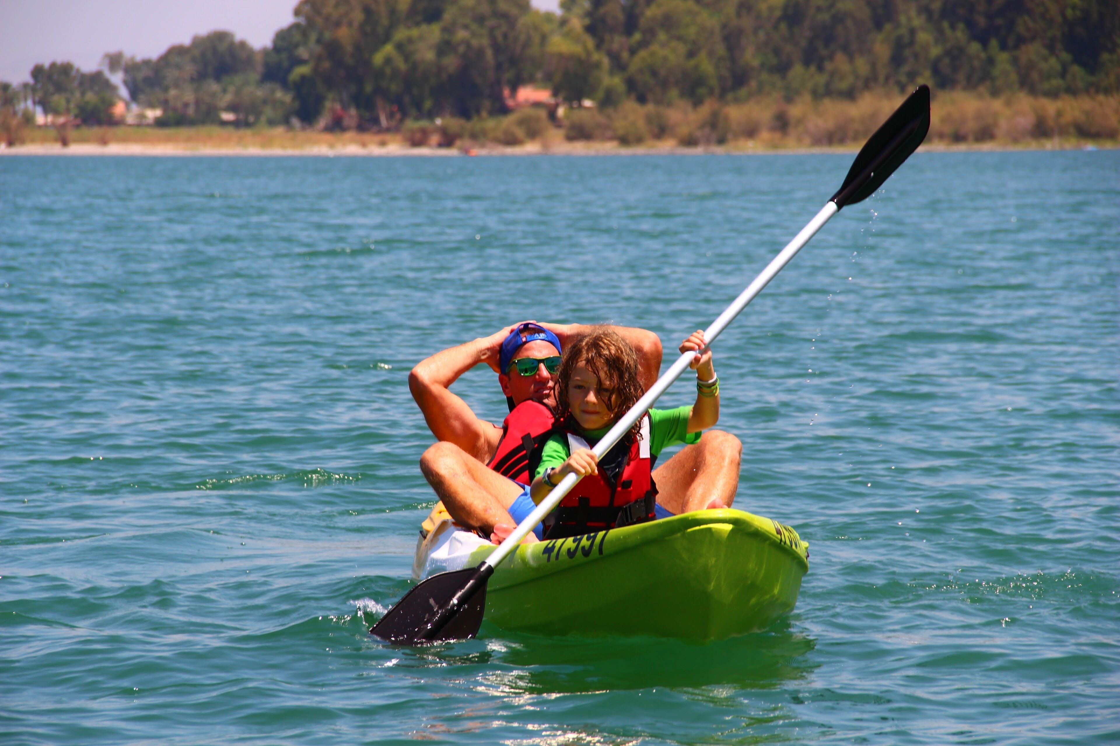 A person in a kayak on a body of water with a forested shoreline in the background.