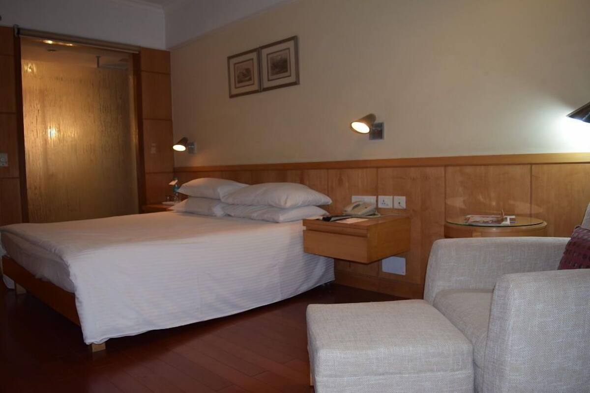 A hotel room with a bed, bedside table, lamp, and a small round table.