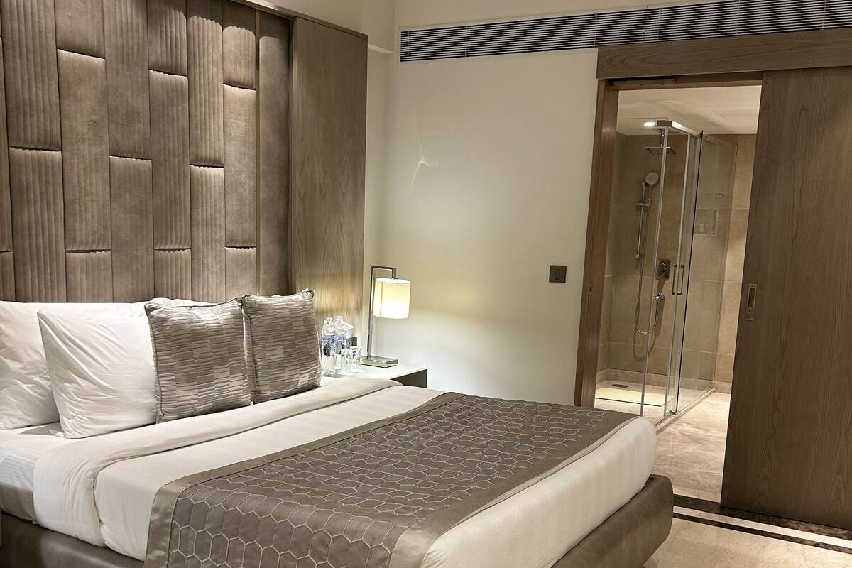A modern bedroom with a large bed, a nightstand, a desk, and a walk-in closet.