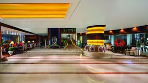 Eine geräumige Lobby mit einer zentralen Treppe, einem Empfangsbereich und Sitzgelegenheiten.