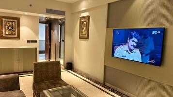 Eine moderne Hotelhalle mit Wandfernseher, einer Sitzecke mit Sofas, einem Glastisch und einer dekorativen Wandverkleidung.