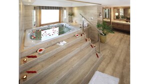 A modern bathroom with a large bathtub, wooden steps, and a potted plant. - Jaypee Vasant Continental (New Delhi)