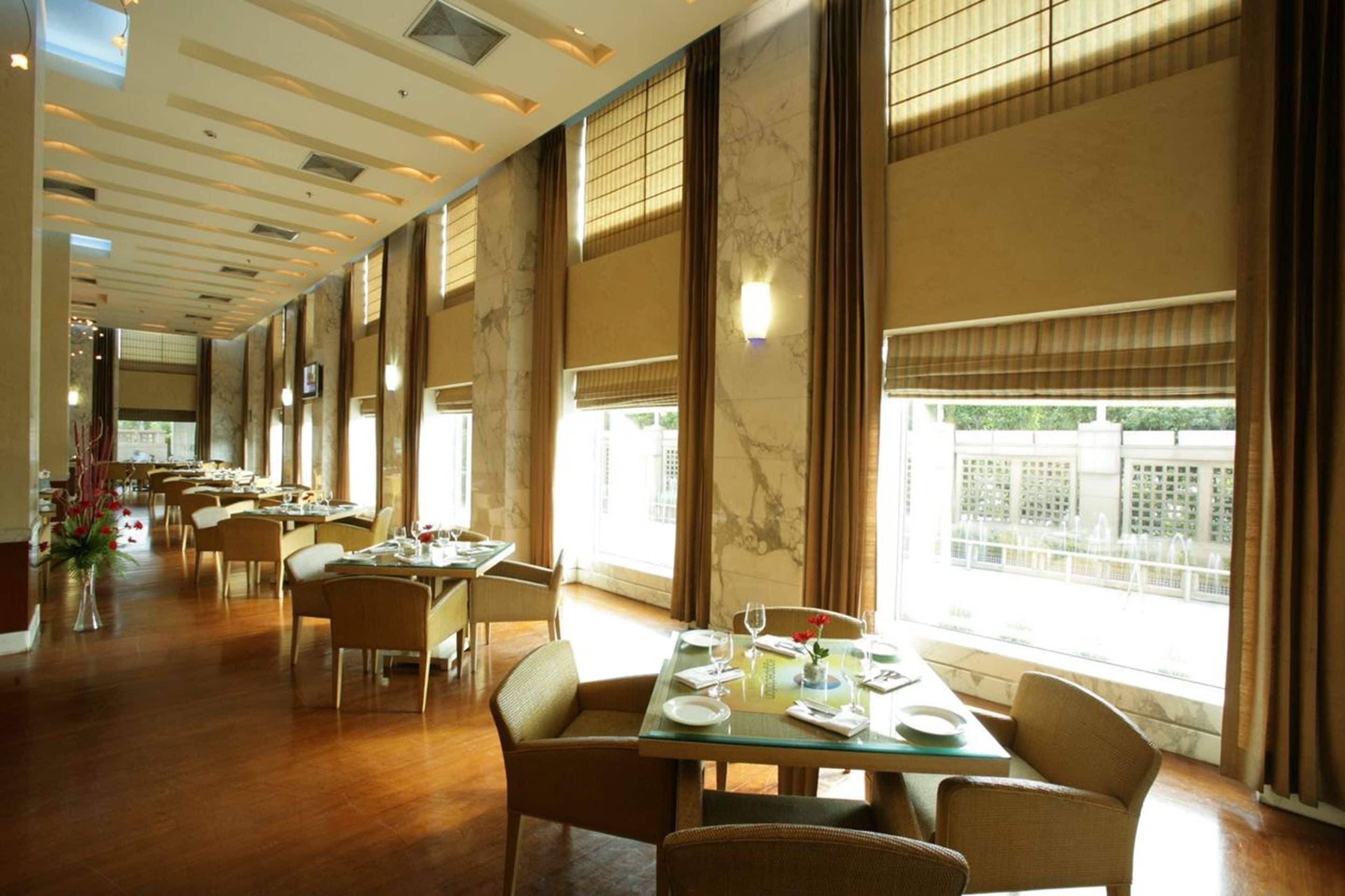 Un amplio comedor con techos altos y ventanas grandes, que incluye varias mesas y sillas.
