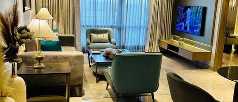 Un salon moderne comprenant un canapé, des fauteuils, une table basse, un téléviseur et un ventilateur de plafond.