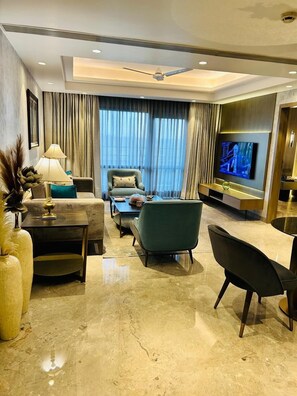Una sala de estar moderna con un sofá, sillones, una mesita de centro, un televisor y un ventilador de techo.