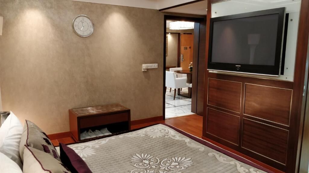 Een hotelkamer met een bed, nachtkastje, televisie en uitzicht op de eetruimte.