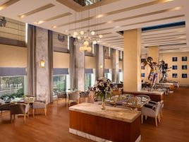 A spacious hotel lobby with high ceilings, large windows, and a central reception area.