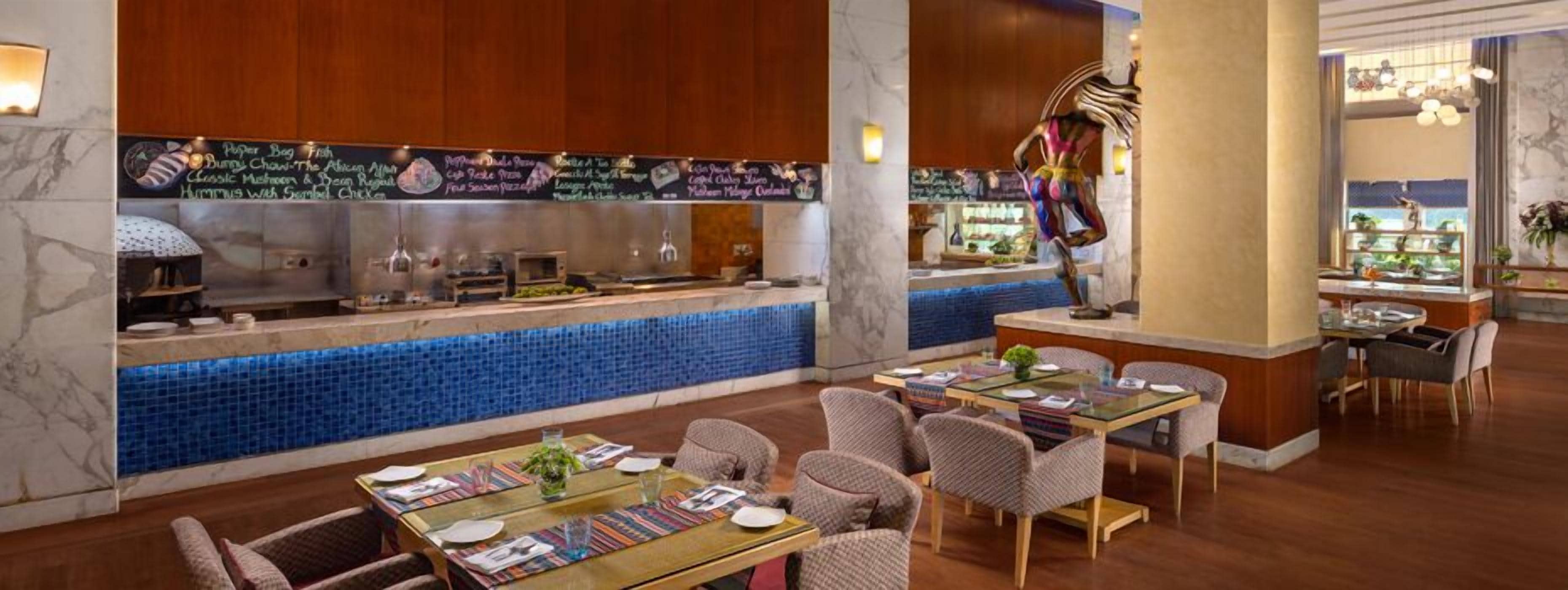 Un ristorante con un'area bar rivestita di piastrelle blu, pannelli in legno e diverse opzioni di seduta tra cui tavoli e sedie.