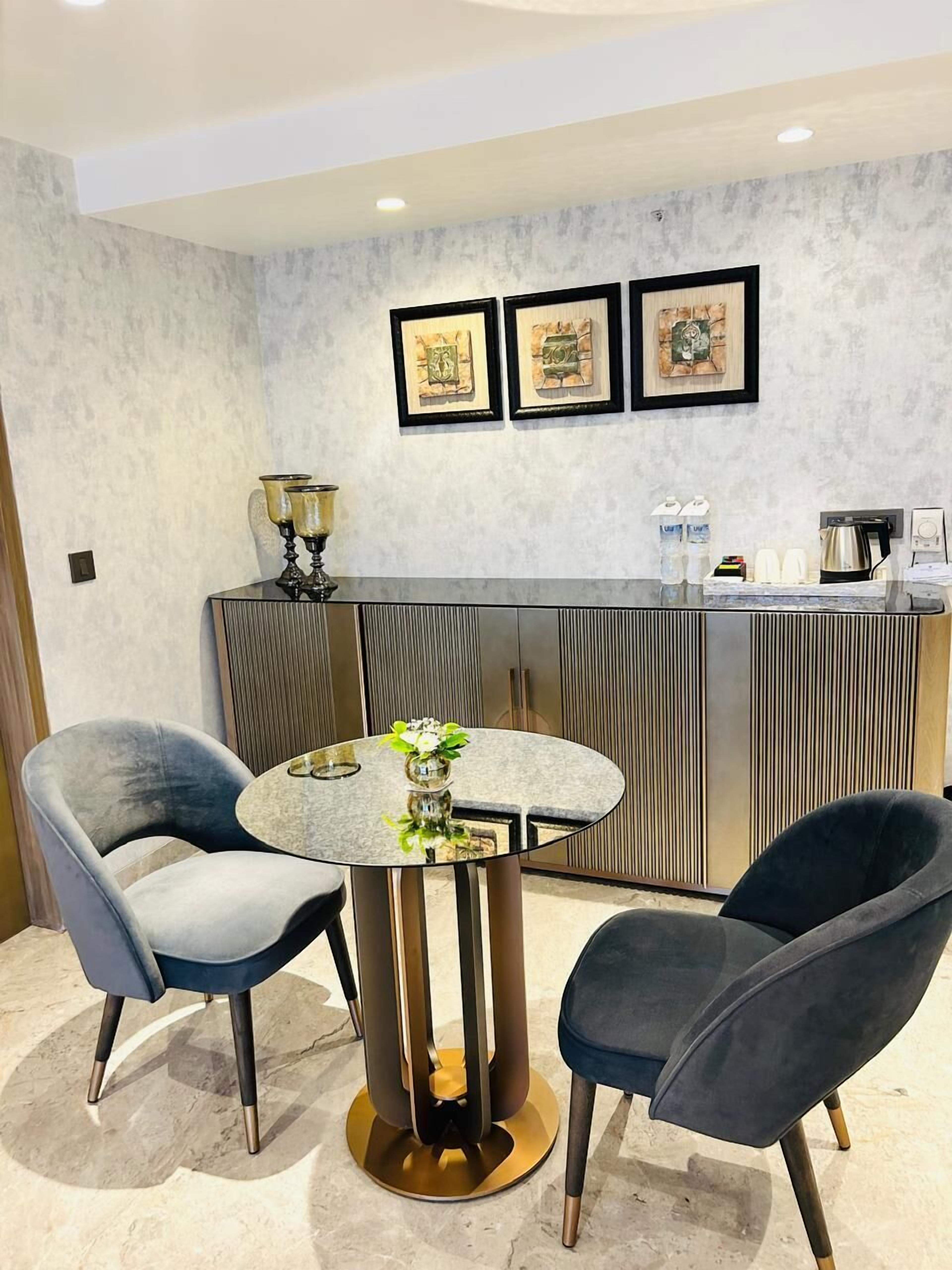 A modern room with a round table, two chairs, a decorative vase, and a counter with framed artwork.
