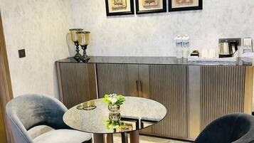 A modern room with a round table, two chairs, a decorative vase, and a counter with framed artwork.