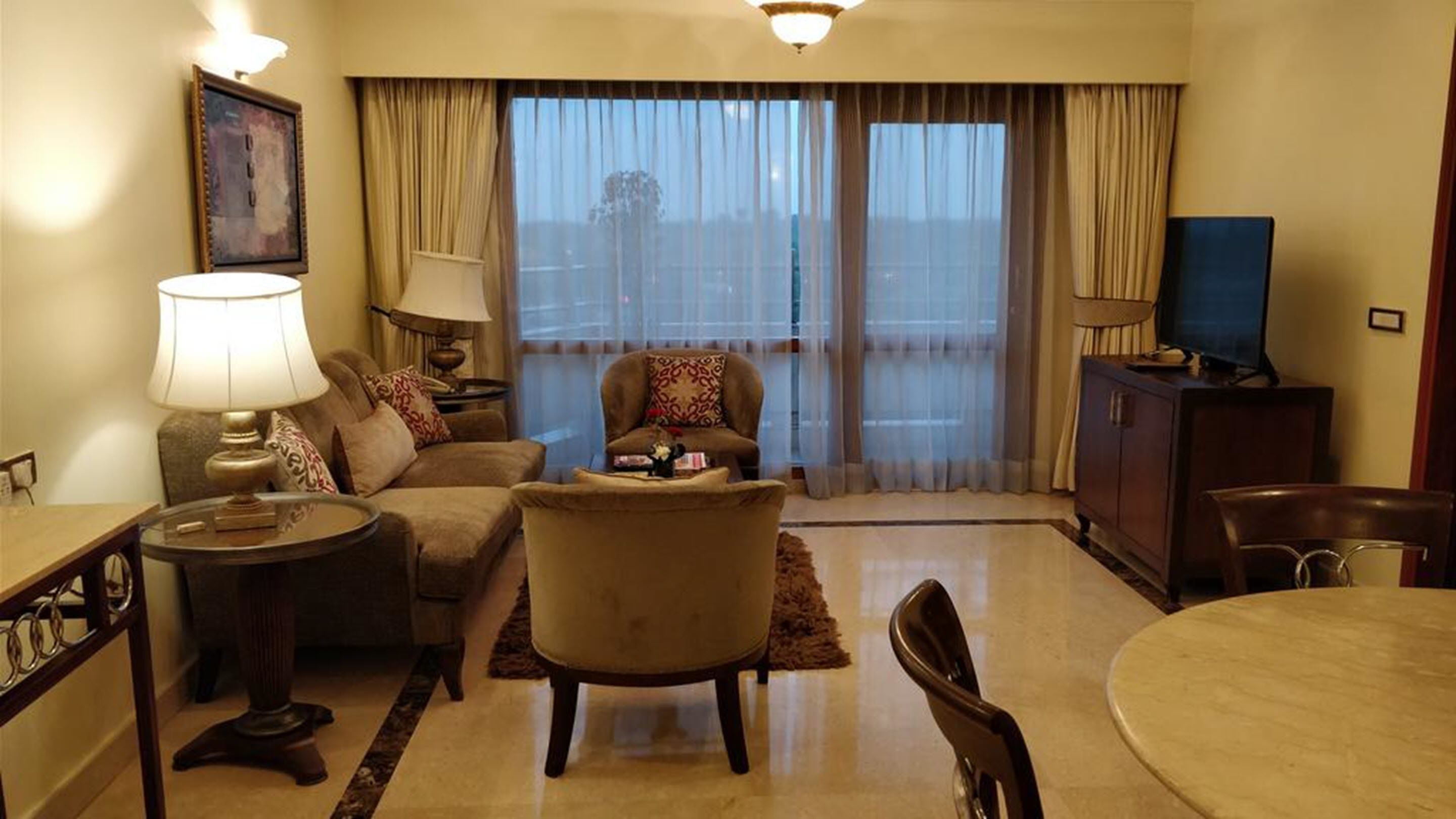 Una sala de estar con un sofá, un sillón, una mesa de centro y un televisor sobre un mueble.