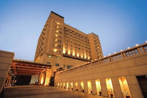 A multi-story hotel with a covered entrance and potted plants along the walkway.