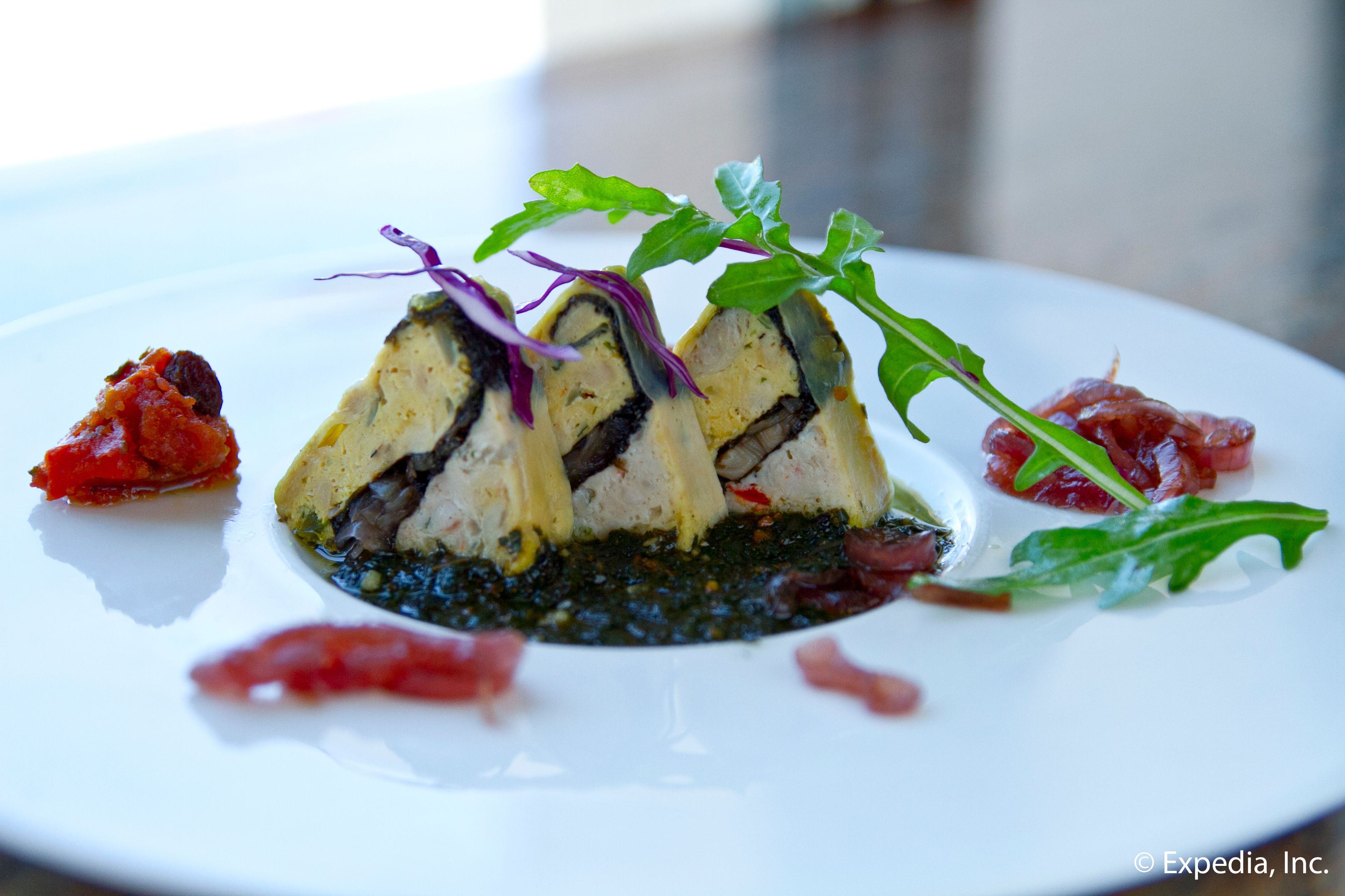 A white plate with a food dish, garnished with greens and red elements.