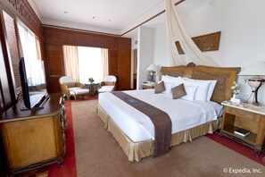 Una habitación de hotel con una cama grande, televisión, escritorio y una silla.