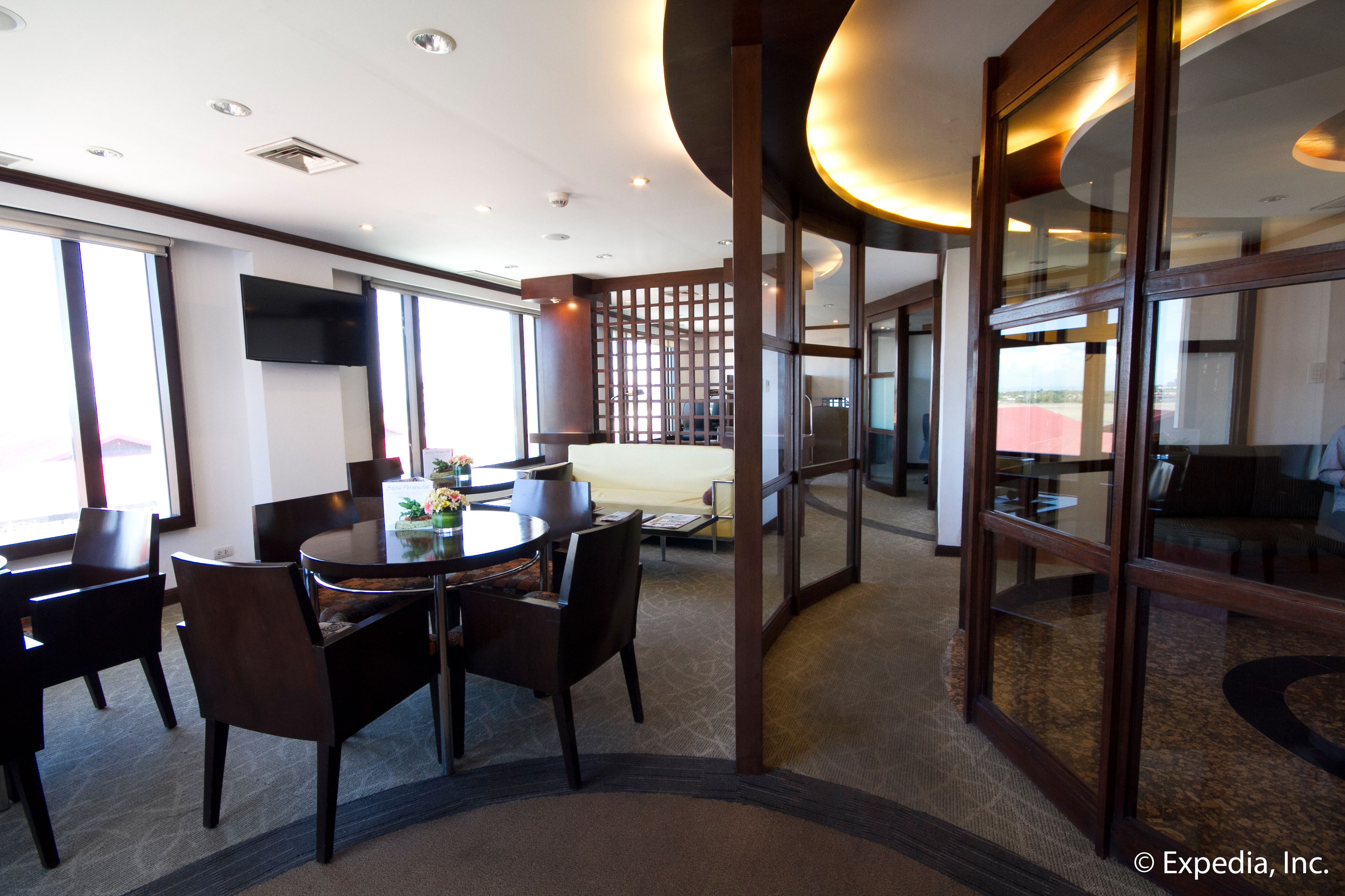 Una habitación de hotel moderna con comedor, ventanas amplias y televisión.