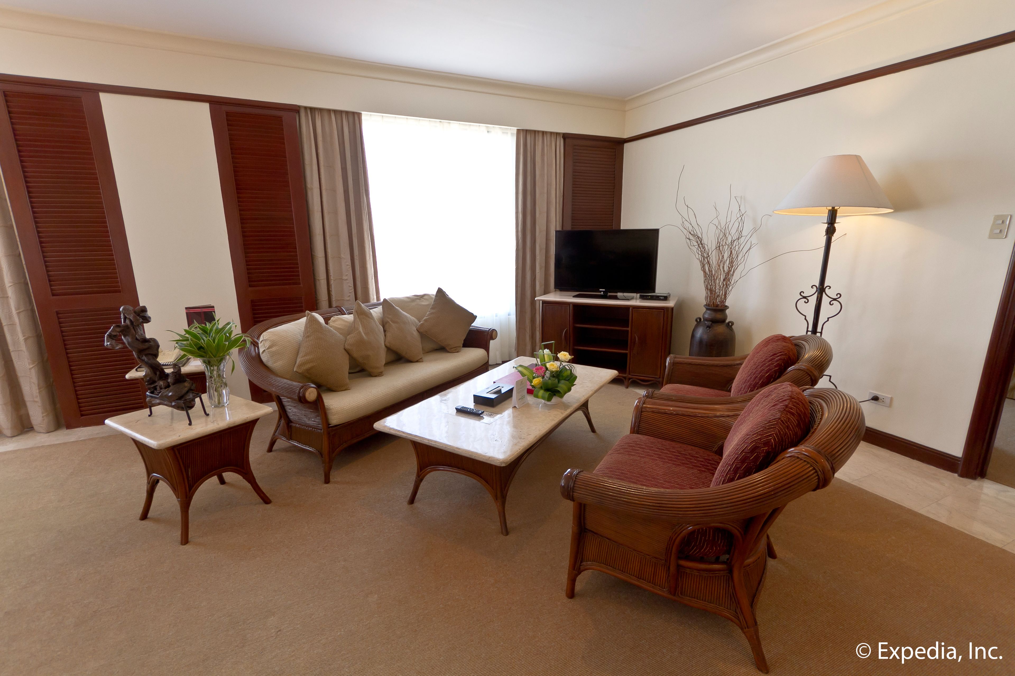A living room with a sofa, armchairs, a coffee table, a TV stand, and a lamp.