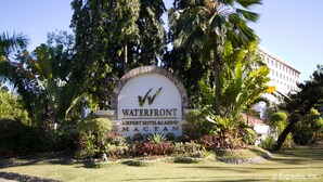 A sign for the Waterfront Airport Hotel & Casino Mactan with a clear view of the surrounding lush greenery and palm trees.