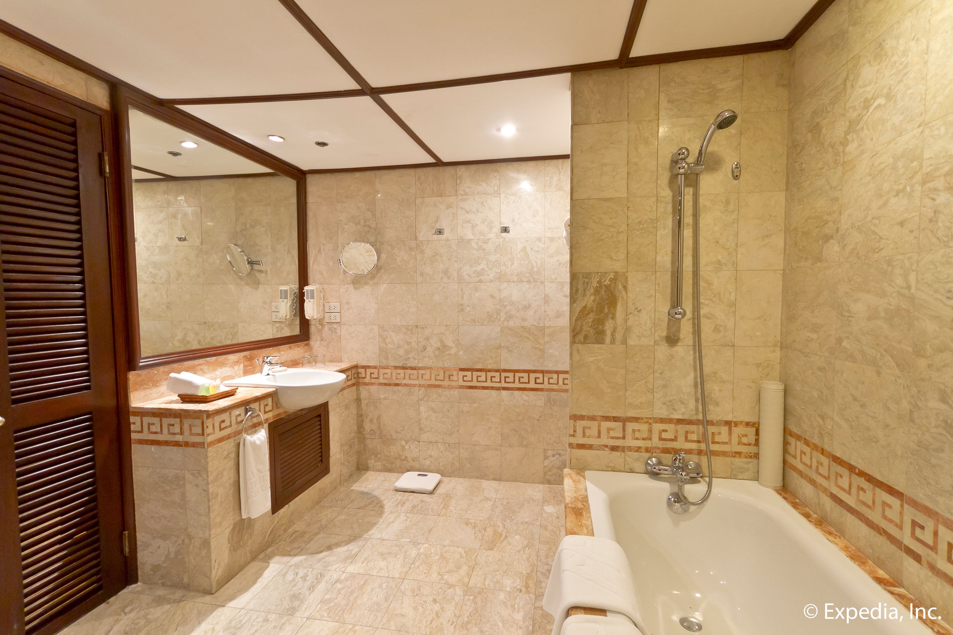A modern bathroom with a bathtub, a vanity with a sink, and a large mirror.