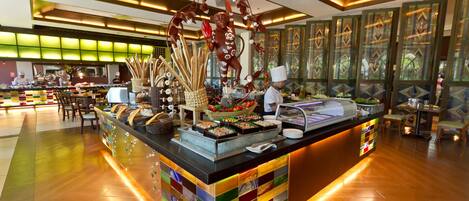 Zona de buffet con una barra de azulejos coloridos, diferentes opciones de comida y una escultura decorativa.
